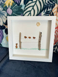 Handmade pebble art shadow box with a cat watching birds perched on a driftwood fence