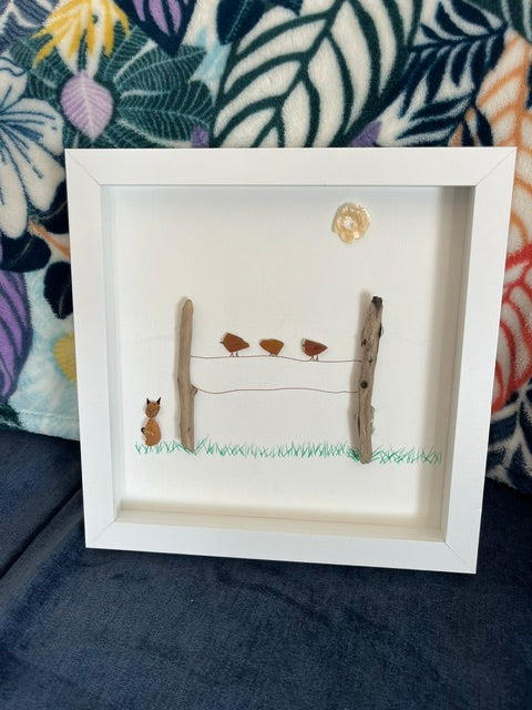 Handmade pebble art shadow box with a cat watching birds perched on a driftwood fence