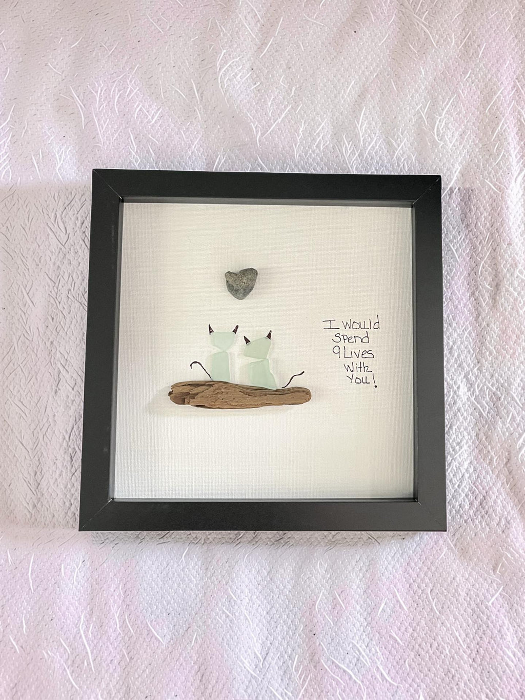 Two sea glass cats on driftwood with a beach stone heart and hand-lettered 9 Lives quote in a dark 8x8 shadow box frame